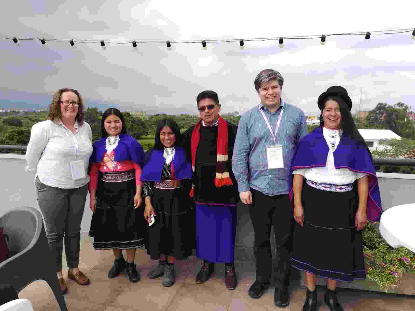 Four members of the Misak indigenous community wearing traditional dress in Colombia smiling and standing together with Claire and Rich from the Water Hub